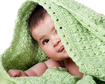 Infant boy with green blanket over his head